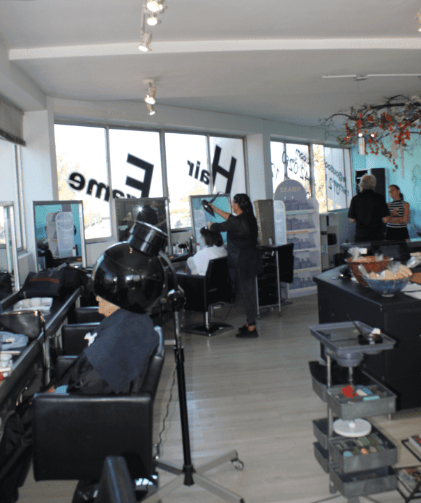 Two clients at Hair Frame Somerset West — one receiving a haircut and styling, the other enjoying a Moroccanoil hair treatment.