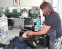 Allan at Hair Frame applying hairspray to client’s hair to add shine and volume during styling.